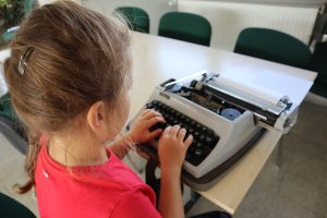 na zdjęciu dziewczynka pisze na maszynie
