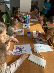 dzieci przy stołach malują farbami bałwanki