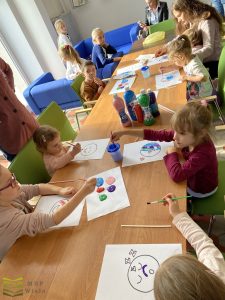 dzieci przy stołach malują farbami bałwanki