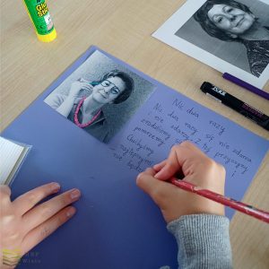 zdjęcie i tekst na fioletowej kartce, ręka dziecka pisze cienkopisem
