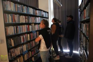 Ciemna, biblioteka, czytelnicy szukają książki na regałach