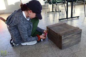 Uczestniczka wybiera kod na kłódce żeby otworzyć drewnianą skrzynię