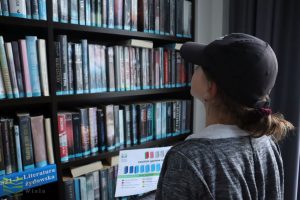 Uczestniczka przegląda książki na regale w dziale dla dorosłych