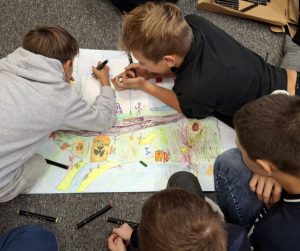 chłopcy rysują na dużym papierze