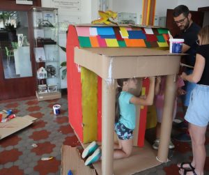 dzieci przy kartonowym domku