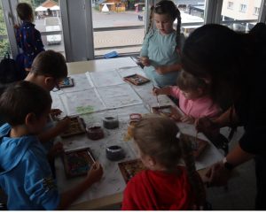 zdjęcie zbiorowe, dzieci pochylają głowy nad pracami plastycznymi